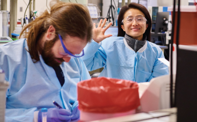 A smiling scientist working together with colleagues in a laboratory setting. A smiling scientist working together with colleagues in a laboratory setting.