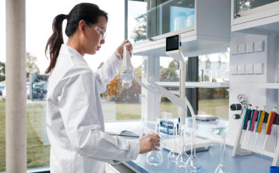 Dispensing of ultrapure water from a Q-POD dispenser Female scientist in a white lab coat is filling volumetric flasks with ultrapure water from a Q-POD dispenser in a modern lab setting with a bright and organized workspace