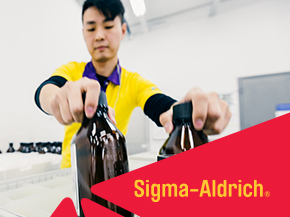 Laboratory scene with a man in a yellow shirt holding two dark bottles, foregrounded by a red Sigma-Aldrich banner.