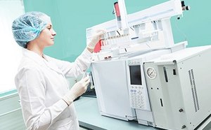 Researcher putting vial in Gas Chromatography instrument Female scientific researcher with lab coat, gloves and hair protection placing vial flask in gas chromatography instrument.