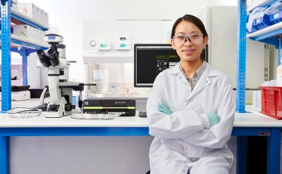 ターゲットの発見 Luminex<sup>®</sup> 装置の横に立ってMILLIPLEX<sup>®</sup> マルチプレックスバイオマーカーアッセイ試薬の箱を持っている研究者と、後ろのベンチ上にあるSMCxPRO<sup>®</sup> 超高感度イムノアッセイ装置